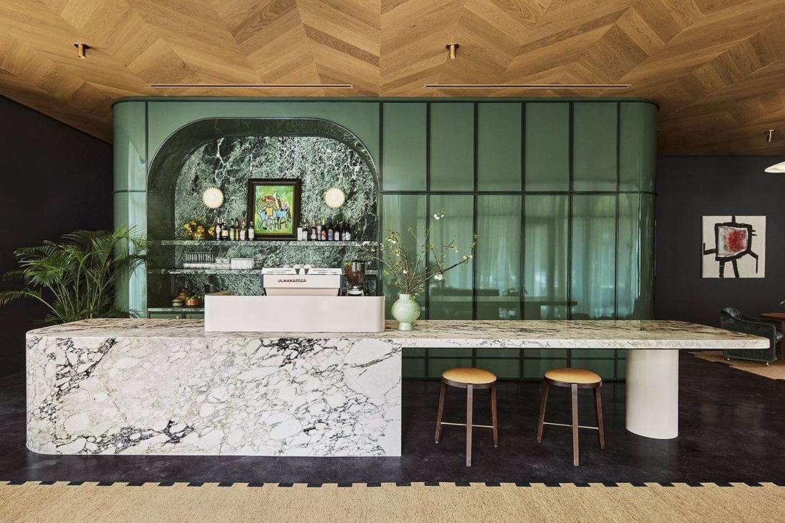 Hotel Henrietta lobby — marble waterfall bar counter and glossy green millwork, New Orleans LA